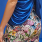 a woman wearing a blue top and a floral skirt