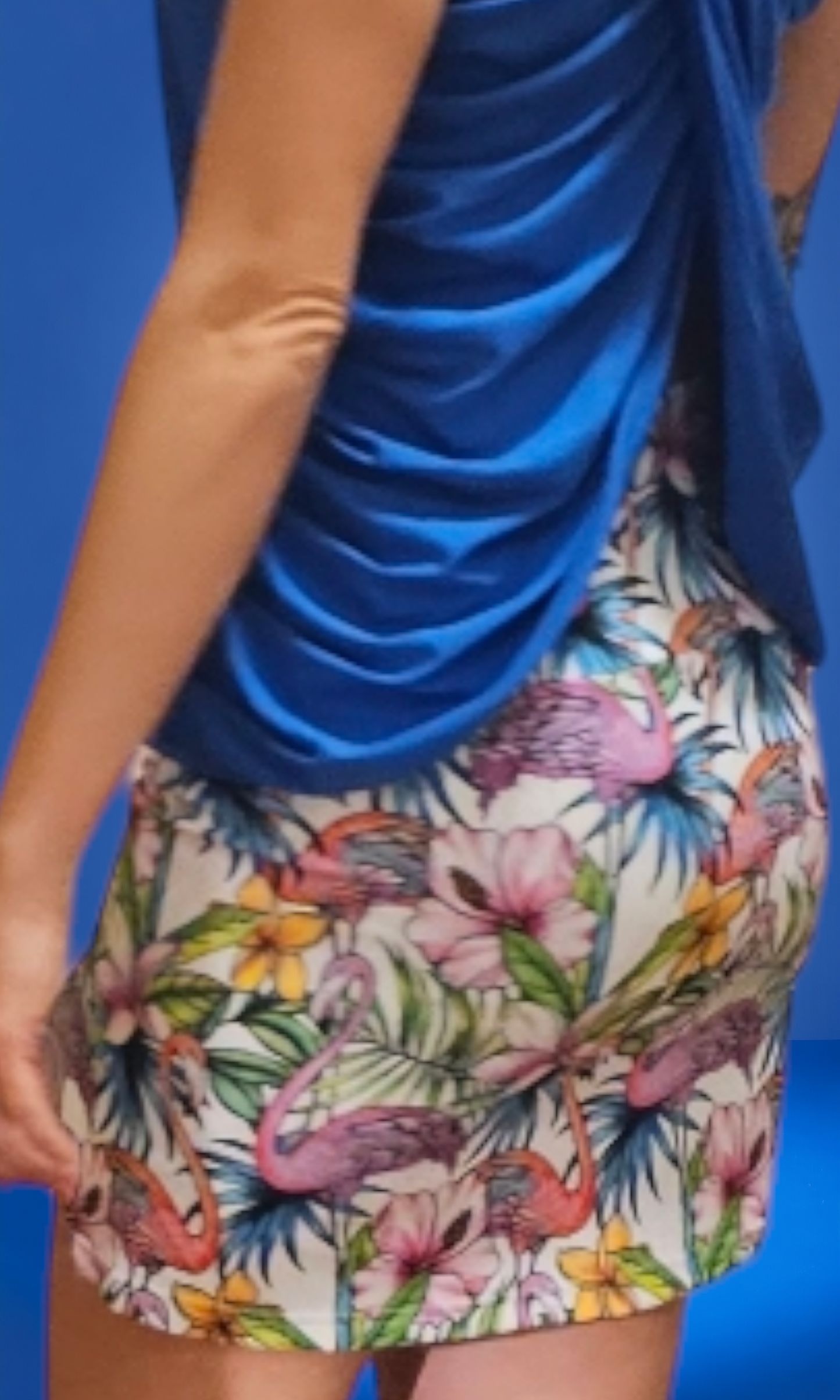 a woman wearing a blue top and a floral skirt