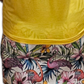 a woman wearing a yellow shirt and floral shorts
